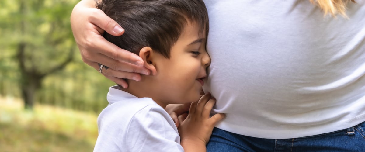 A young boy hugs his pregnant mother