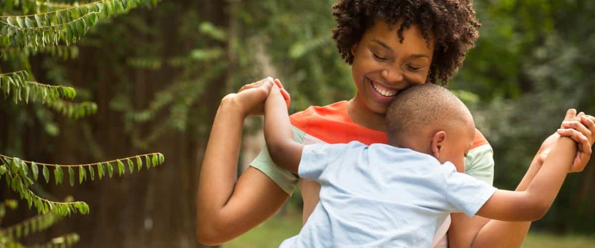 A smiling Black mother holds her baby