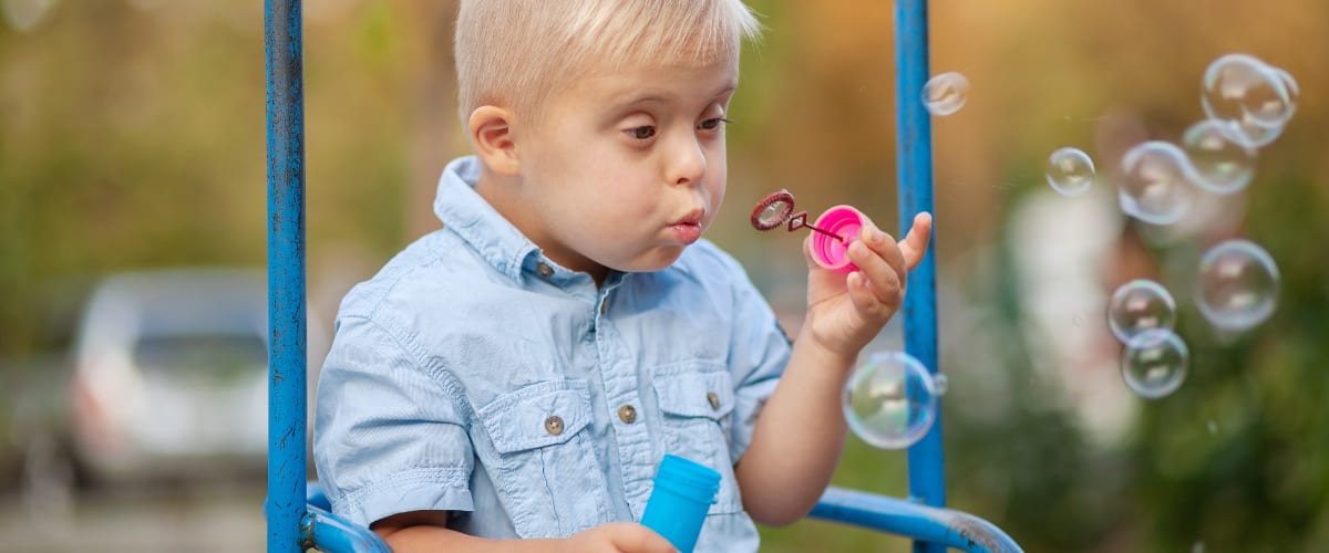 A young boy with Down Syndrome blows soap bubbles